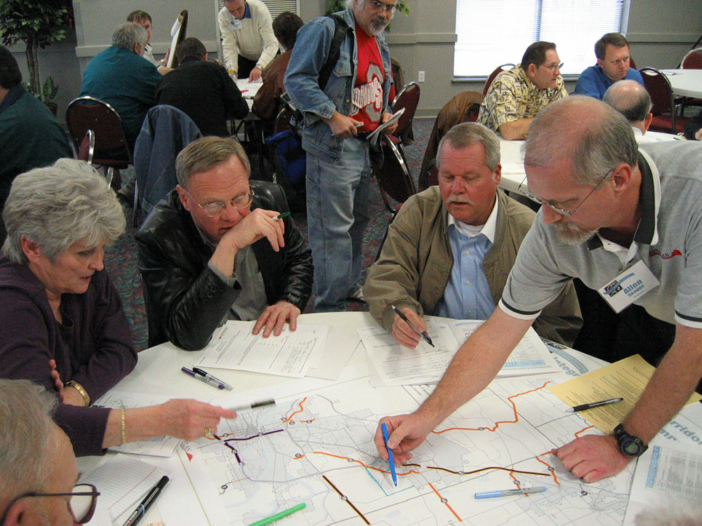 People leaning over a table with a map on it.